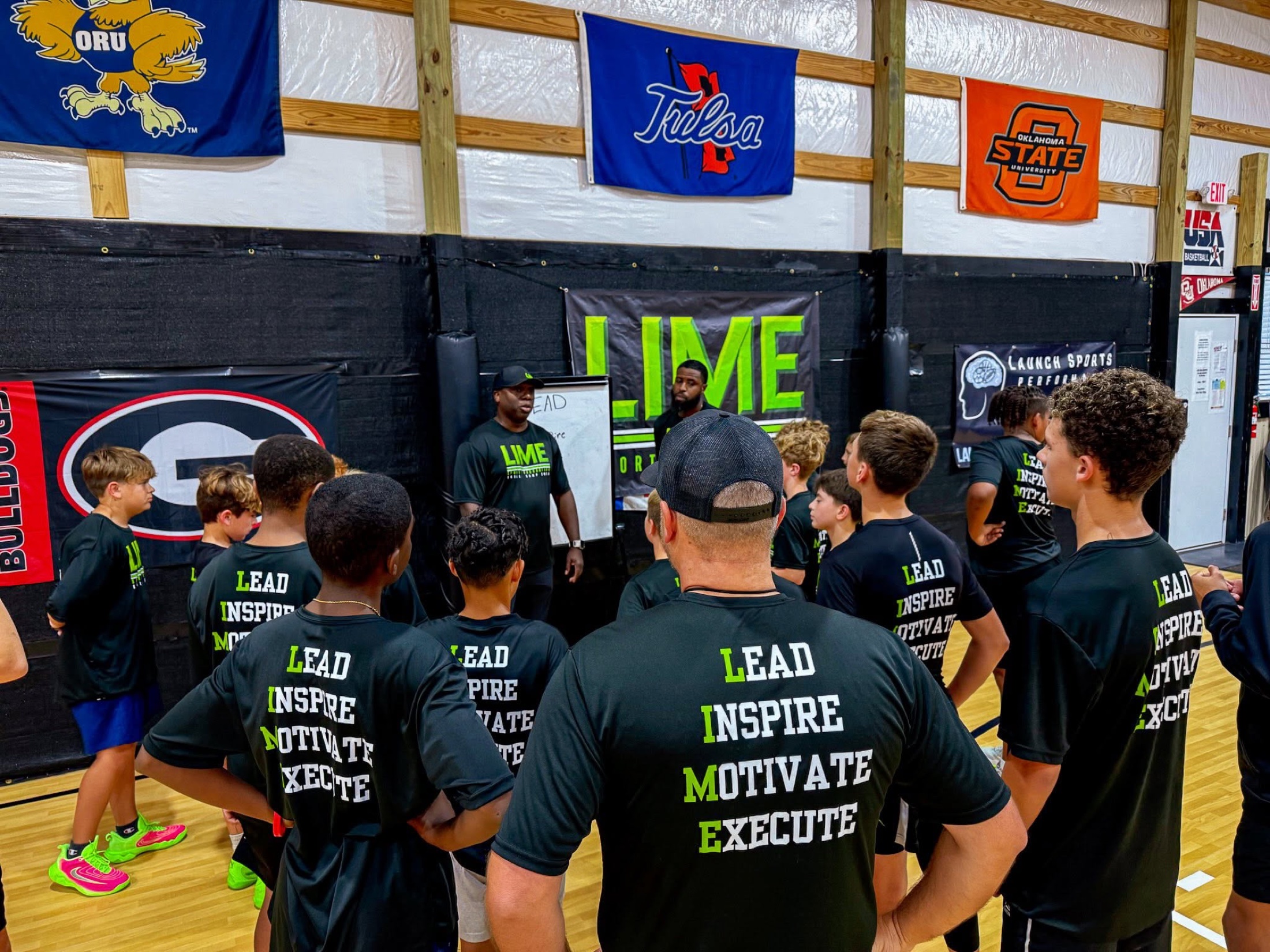 LIME coaches leading a basketball camp talk with young athletes gathered around them